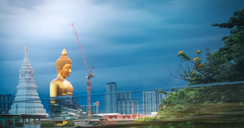 Statue against temple and building against sky