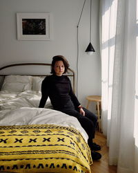Portrait of woman sitting on bed at home