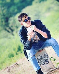 Full length of boy holding sunglasses standing outdoors