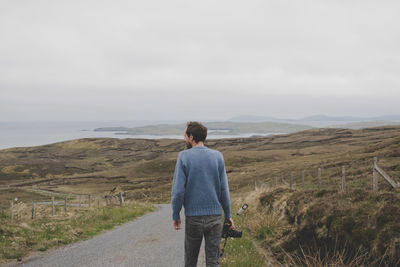 Rear view of man standing on road against sky