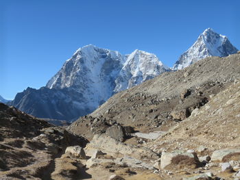 Scenic view of snowcapped mountains against clear blue sky