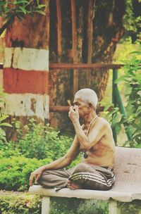 Man sitting on statue against trees