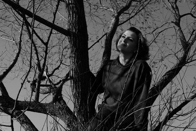 Young woman looking away while standing on tree trunk