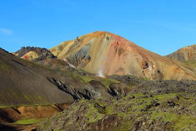 Scenic view of volcanic mountain against blue sky