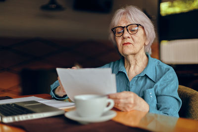 Senior businesswoman reading document in cafe