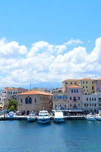 City at waterfront against cloudy sky