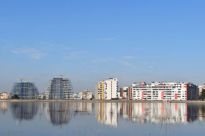 Reflection of buildings in city against blue sky