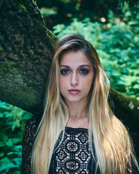 Portrait of young woman standing against tree