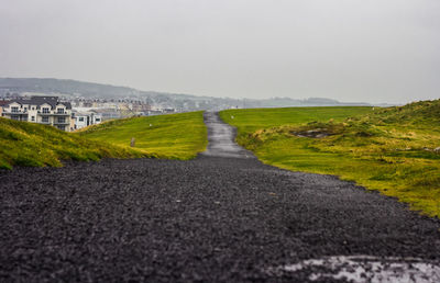 Road amidst land against sky in city