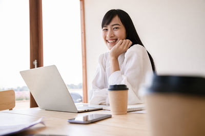 Young woman using phone while sitting on table