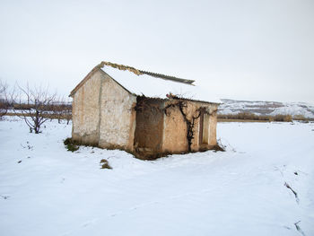 House on snow covered field against sky