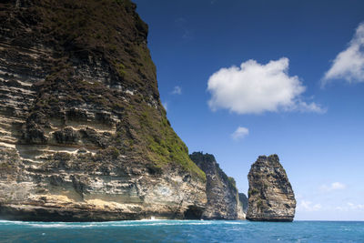 Rock formations by sea against blue sky