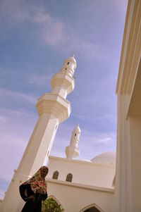 Teenage girl wearing traditional clothing standing against mosque during sunny day