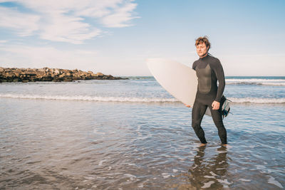 Full length of man standing on beach against sky