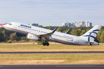 Airplane flying over airport runway against sky