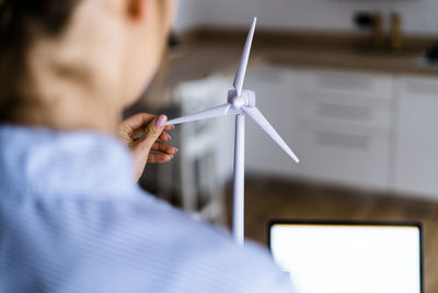 Close-up of woman turning wind turbine modell in office