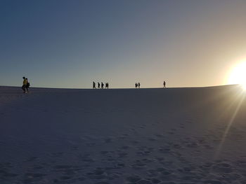 People on beach against sky during sunset