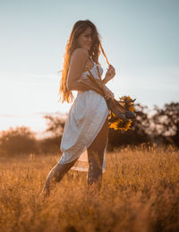 Woman with arms raised on field against sky