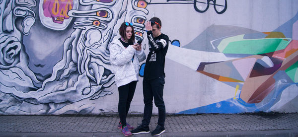 Full length of young man standing against graffiti wall