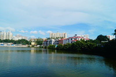 Buildings by river against sky in city