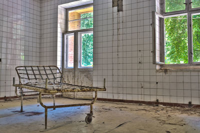 Rusty metal bed on floor in abandoned hospital