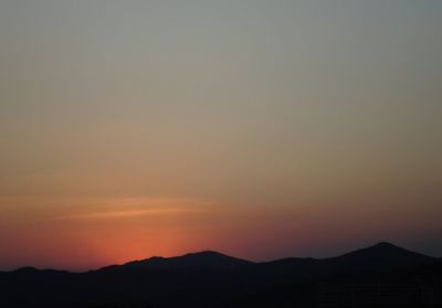 Scenic view of silhouette mountains against romantic sky at sunset