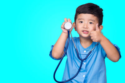 Portrait of boy holding blue background