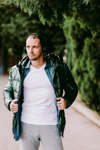 Handsome man listening music while standing in park