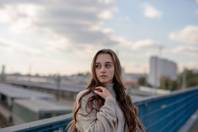 Young woman looking away while standing by railing