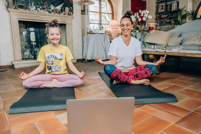 Full length of mother and daughter sitting on floor at home