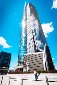 Low angle view of man standing against blue sky