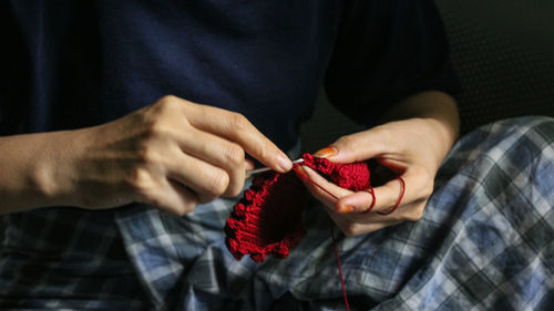 Midsection of person knitting red wool