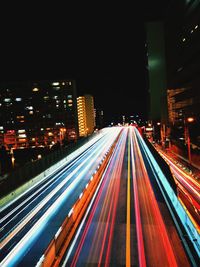 Light trails on city street by buildings at night