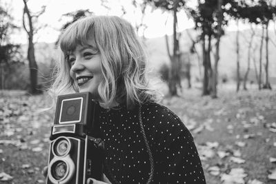 Close-up of woman with vintage camera against trees