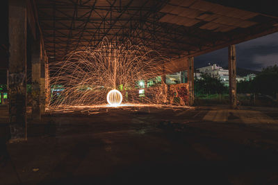 Light trails on illuminated city against sky at night