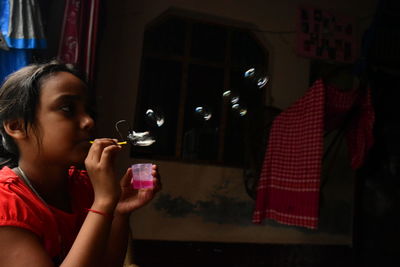 Girl blowing bubbles at home