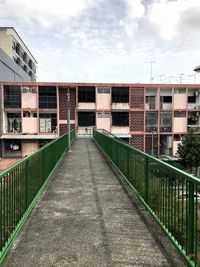 Footpath amidst buildings in city against sky