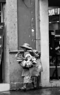 Rear view of woman holding umbrella against building in city