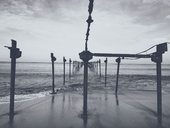 Wooden posts on beach against sky