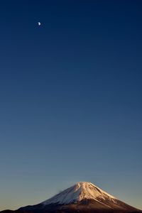 Low angle view of volcanic mountain against blue sky