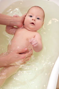High angle view of shirtless baby boy in bathtub