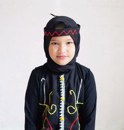 Portrait of smiling young woman standing against white background