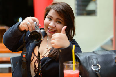 Portrait of smiling woman holding camera