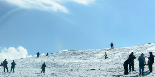 People on snow covered land against sky