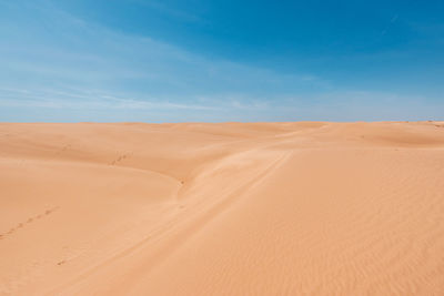 Sand dunes in desert against blue sky