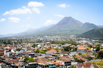 Aerial view of townscape and mountains against sky