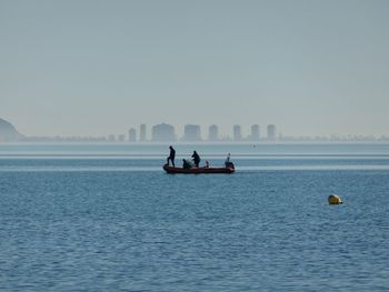 People kayaking in sea against clear sky