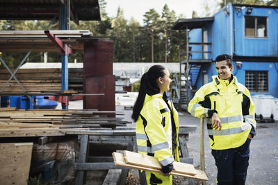 Happy carpentry students in reflective clothing talking outside school