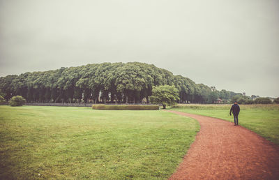 Man walking on field against sky