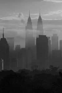 Trees and buildings against cloudy sky during sunset